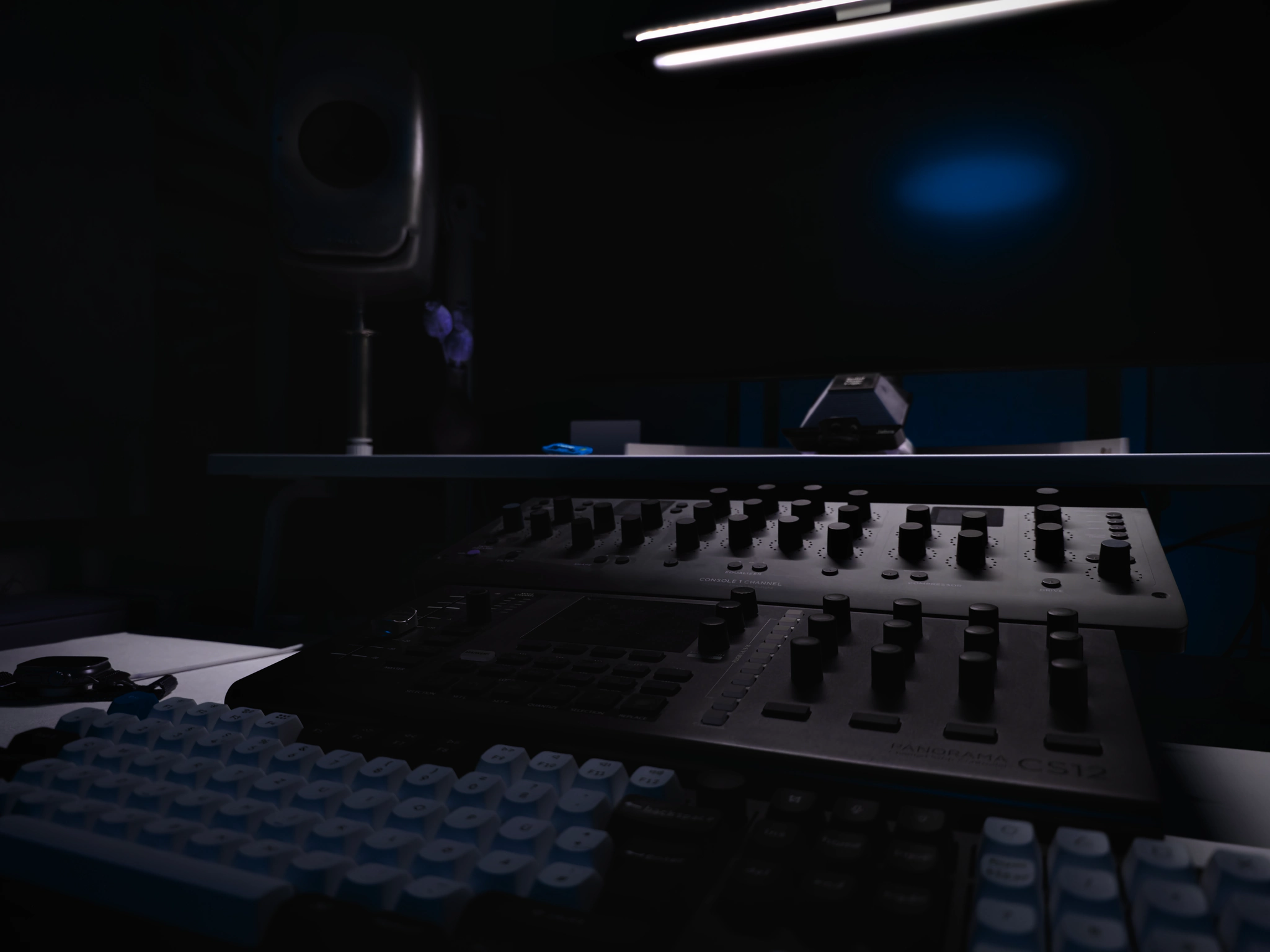 Console channel strip and controller on the studio desk in dim blue light