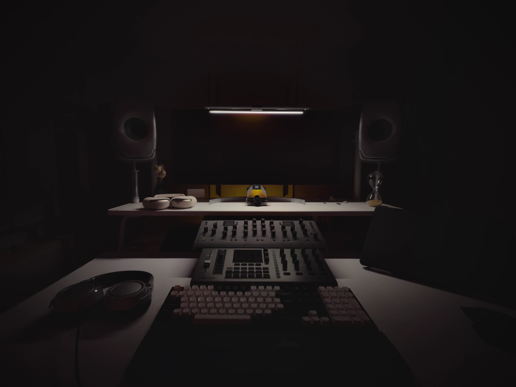 Studio desk at night with monitor speakers, controllers and a dimmed light bar