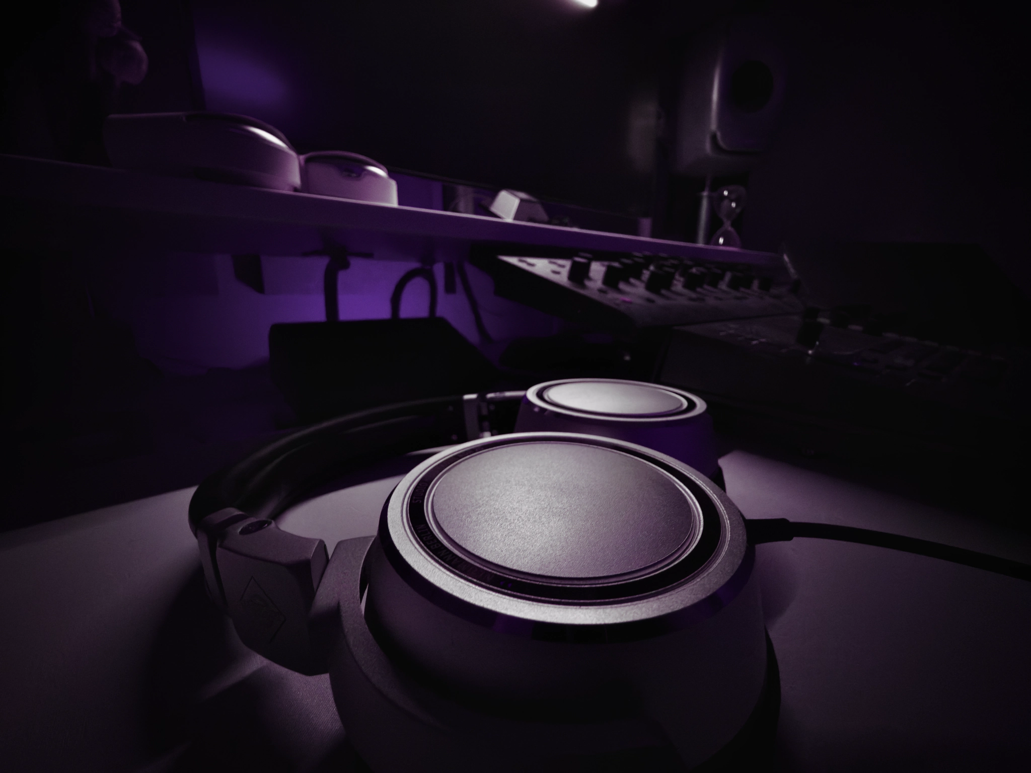Close-up of studio headphones with the mixing desk blurred behind